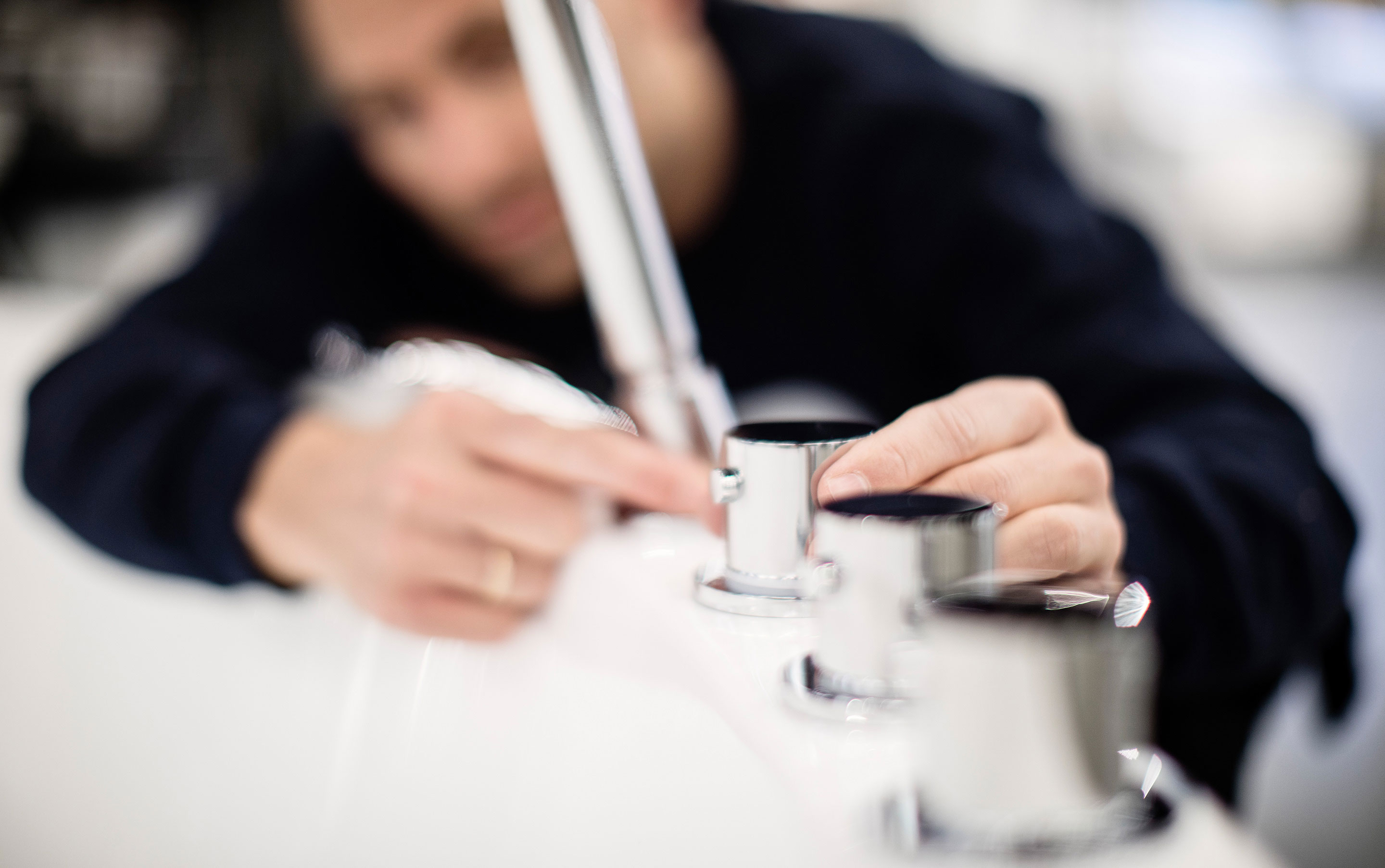 Rørlegger monterer badekarbatteri. Uskarpt bilde.